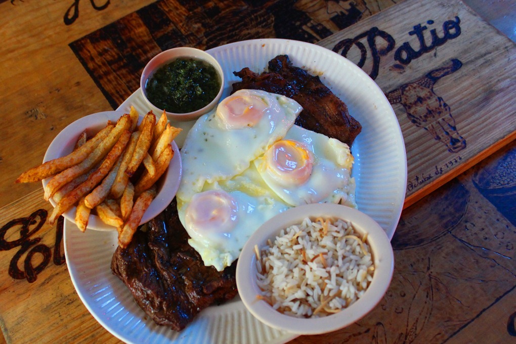 Bistec con tres huevos estrellados y papas fritas.